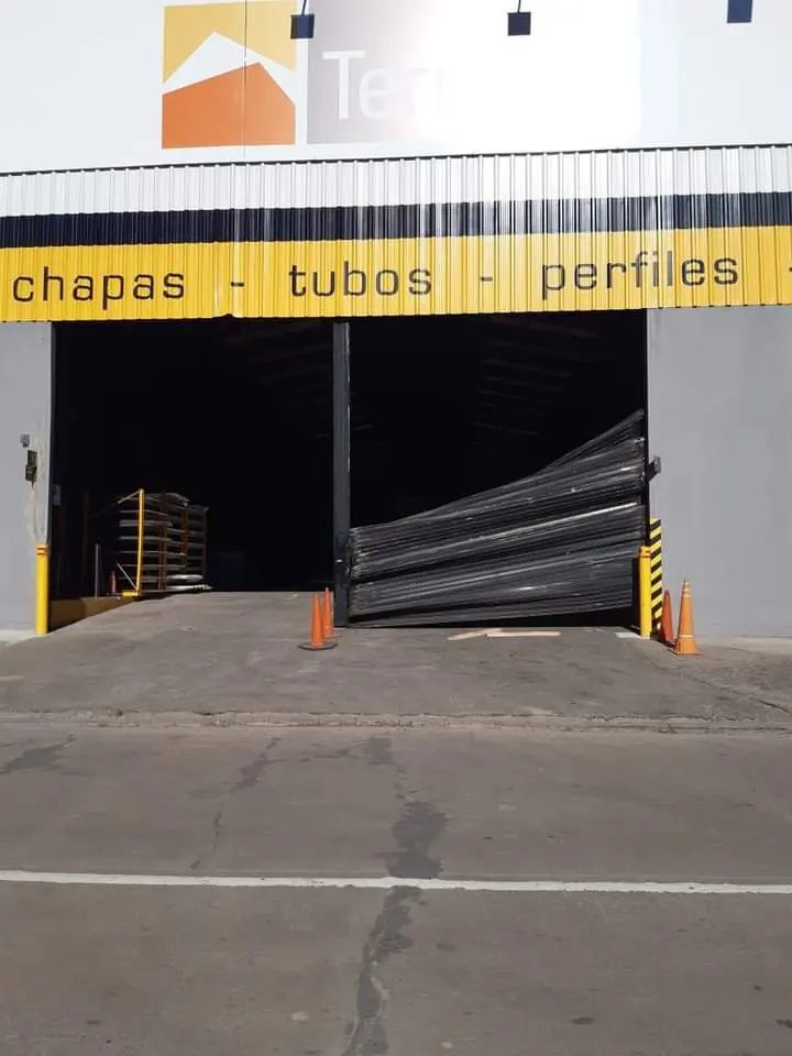 Cortina metálica dañada en depósito industrial, de reparar
